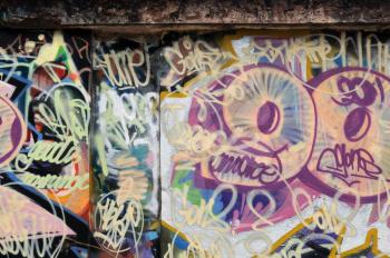 Grunge wall covered with colorful layers of messy graffiti tags. Urban background.