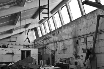 Smashed equipment in decaying interior of abandoned factory. Black and white.