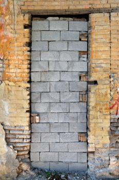 Bricked up door and chipped brick wall texture. Abandoned house exterior.