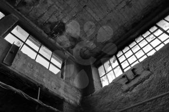 Broken windows concrete wall and ceiling in derelict factory. Black and white.