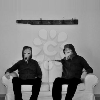 Two figures with dog mask sitting on couch. Black and white.