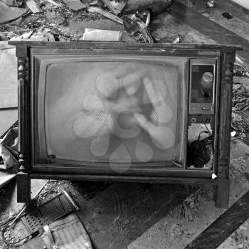 A ghostly figure appears on the flickering screen of an old tv set. Haunted house.