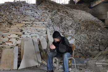 Man sitting next to pile of broken marble in abandoned interior. Motion blur.