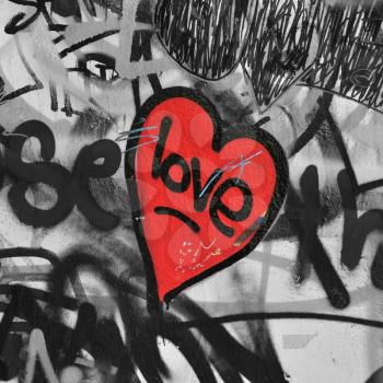 Red painted love heart on graffiti covered black and white wall background. Selective saturation.