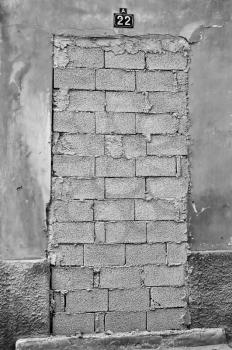 Bricked up door and weathered wall of an abandoned building. Black and white.