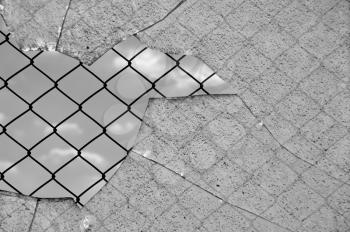 Broken glass and chain link wired fence against the sky. Black and white.