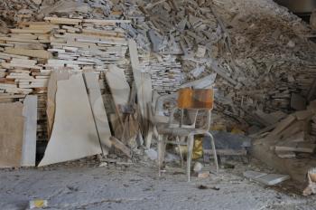 Dusty chair and pile of broken marble in abandoned factory interior.