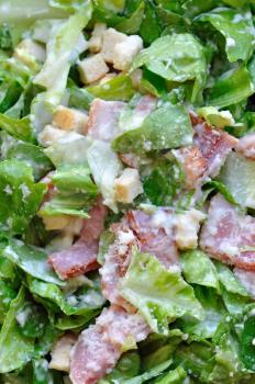 Caesar salad with lettuce, bacon and croutons. Food background.