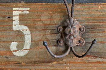 Rusty coat hook hanger with bizzare male figure on wooden vintage clothes rack.