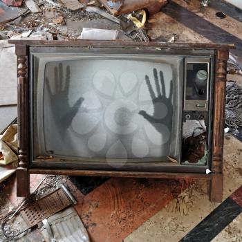 Ghost emerges through broken flickering television screen in haunted house.