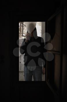 Broken window and man holding a piece of glass in abandoned house.