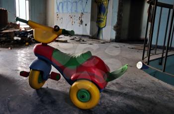 Little kids tricycle toy bike in abandoned house decayed interior. Social issues.
