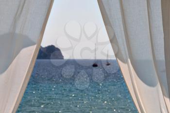 White curtains window view to sea and boats. Summer abstraction, focus on the drapes.