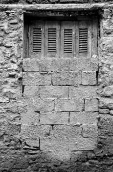 Bricked up window and textured wall abandoned house exterior. Black and white.