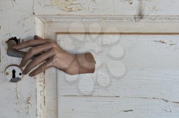 Doll hand opening a closed door in haunted house.