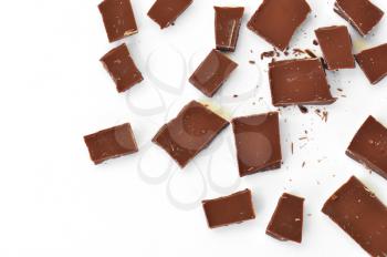 Pieces of milk chocolate on white background.