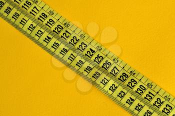 Plastic tape measure inches and centimeters. Abstract numbers yellow background.