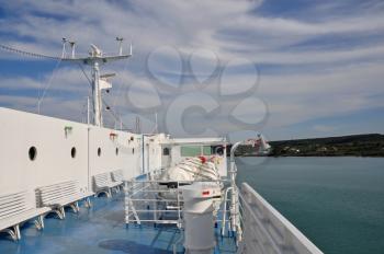 Ship deck with benches, portholes and inflatable liferafts. Sea and sky horizon travel background.