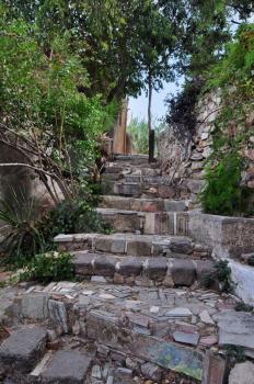 Stone steps decorated with ancient Greek symbols. Picturesque narrow street below the Acropolis rock in Plaka, Athens Greece.