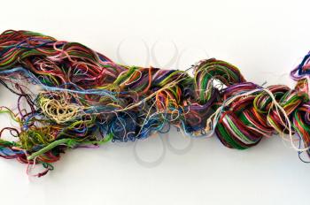 Tangled colorful sewing threads on white background.