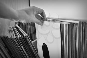 Crate digging through vinyl records music collection. Black and white.