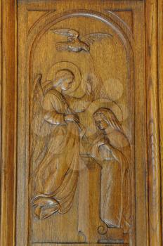 Annunciation of Virgin Mary religious scene carved on antique wooden door from 1927.