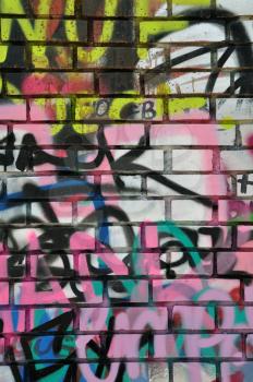 Brick wall covered with messy graffiti. Abstract grungy background.