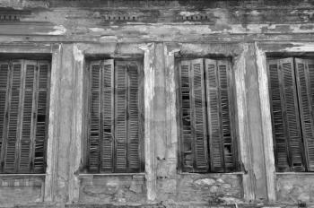 Broken wooden window shutters and textured wall of an abandoned house. Urban decay black and white.