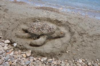 Sea turtle sand sculpture on sandy beach. Summer holidays.