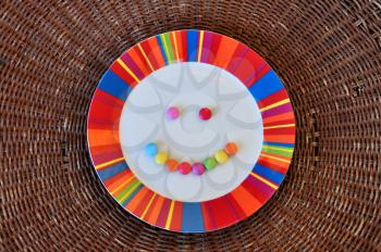 Plate with smiling face made from colorful candy. Abstract food background.