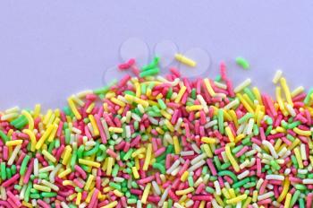 Colorful candy sprinkles garnish sweet food topping on white background.