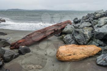 Driftwood logs sit on the shoreline at Alki Beach in West Seattle, Washington.