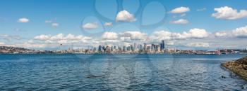 A panorama view of the Seattle skyline with puffy clouds above.