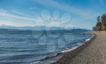A view of a fisherman and the Olympic Mountains from Lincoln Park in West Seattle, Washington.
