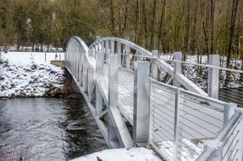 A view of a metal bridge that spans the Cedar River in Renton, Washington. Snow covers the bridge and ground.