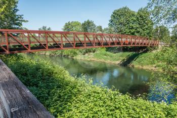 A rusty metal walking bridge spans the Green River in Kent, Washington.
