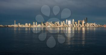 As the sun sets the buildings of the Seattle skyline are relfected in Elliott Bay.