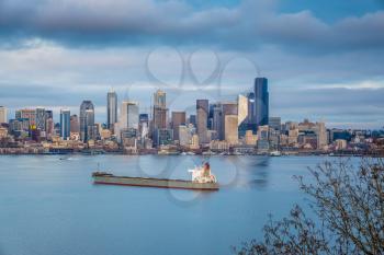 A large ship  lays anchored in front of the Seattle skyline.