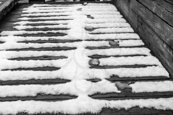 Snow melts on a wooden walkway creating an interesting pattern.