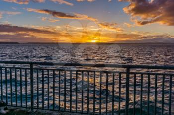 A view of a fence and golden sunset  across the Puget Sound from West Seattle, Washington.