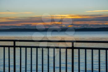 A view of a sunset with a fence from West Seattle, Washington.