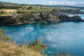 A yacht is anchored in a cove on the Northwest Maui shoreline.