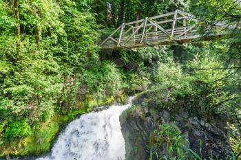A waterfall bulges out with water in Tumwater, Washington. A bridge is above.