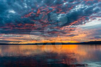 Clouds hang in the sky as the sun sets behind the Olympic Mountains in Dash Point, Washington..