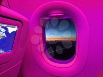 Airplane cabin window with pink light glow and map