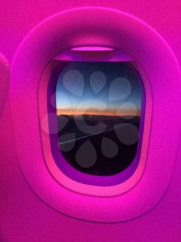 Oval Airplane cabin window with pink light glow