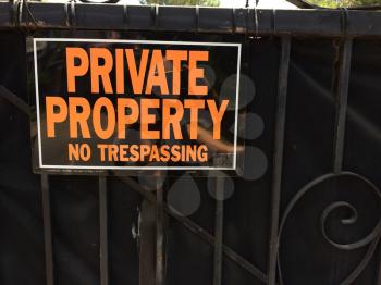 Private property no trespassing sign orange and block on gate