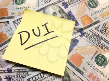 American cash money and yellow post it note with text DUI in black color aerial view