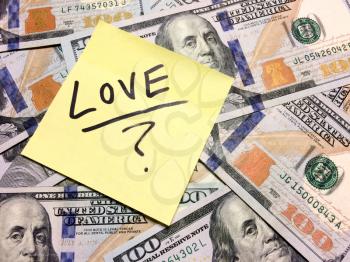 American cash money and yellow post it note with text Love with question mark in black color aerial view