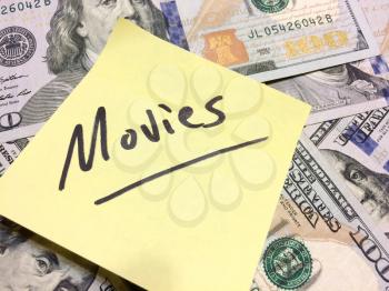 American cash money and yellow post it note with text Movies in black color aerial view